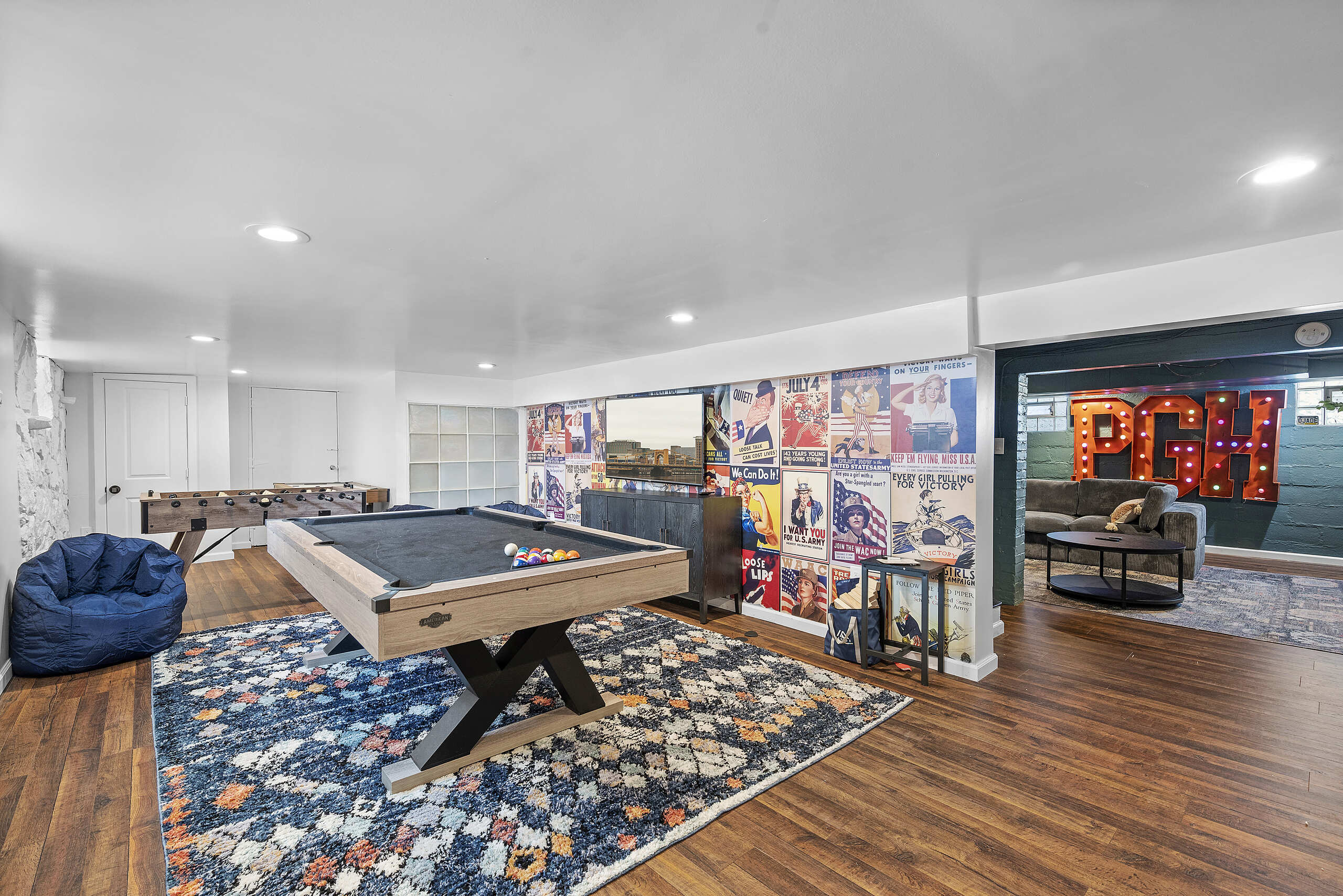 After renovation, a vibrant recreational room in a vacation rental featuring a pool table, modern decor, and lively wall art.