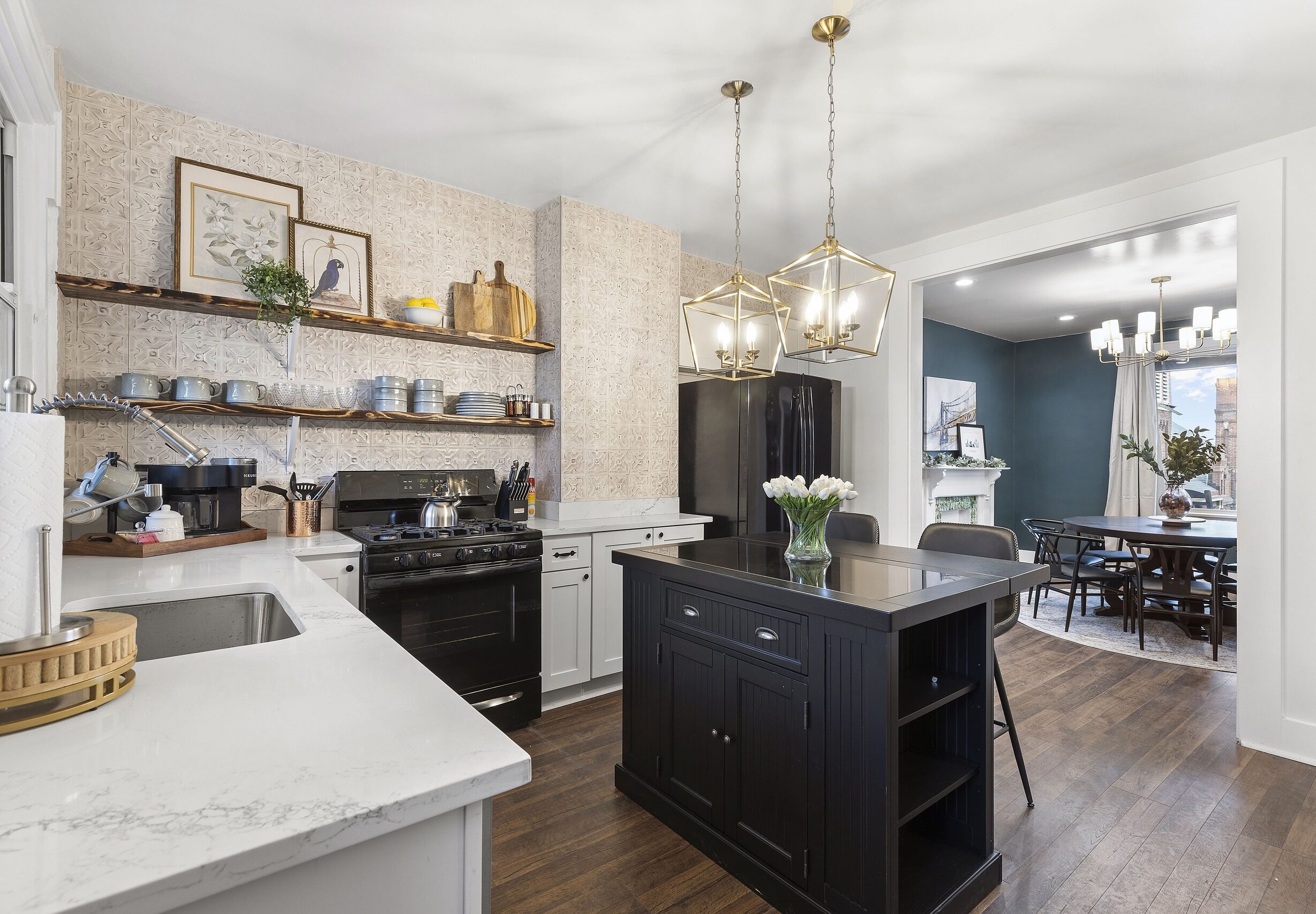 Modern, renovated kitchen in a vacation rental, featuring white countertops, black appliances, and elegant pendant lighting.