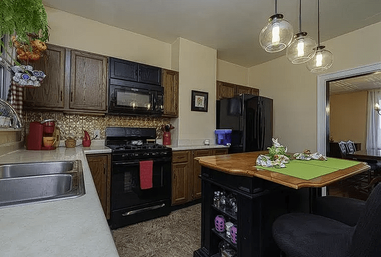 Outdated kitchen with dark wood cabinets and cluttered countertops before renovation.