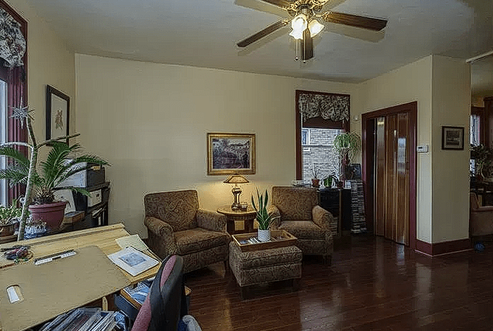 Before renovation, a living room with dated furniture and plain walls.
