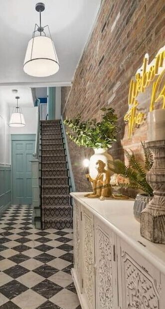 Welcoming entryway with 'Hello Sunshine' neon sign and sophisticated decor in a short-term rental property.